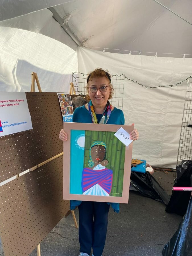 HSU Spanish Professor Margarita Peraza-Rugeley shows off a painting she just sold at the Arkadelphia Festival of the Arts.