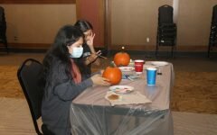 Two students sitting together readying to paint their pumpkin.