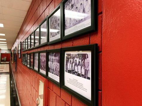 Team pictures of Henderson volleyball lined up on wall in Duke Wells center.